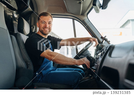 Cheerful smile, looking at the camera. Inside of the bus with delivery service man in uniform Cheerful smile, looking at the camera. Inside of the bus with delivery service man in uniform 139231385