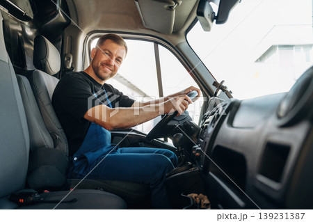 Cheerful smile, looking at the camera. Inside of the bus with delivery service man in uniform Cheerful smile, looking at the camera. Inside of the bus with delivery service man in uniform 139231387