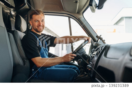 Cheerful smile, looking at the camera. Inside of the bus with delivery service man in uniform Cheerful smile, looking at the camera. Inside of the bus with delivery service man in uniform 139231389