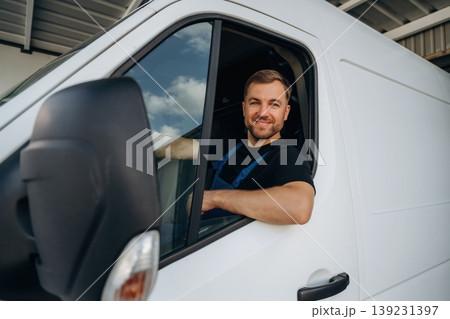 Sitting in a van and smiling. Courier of delivery service company is at work Sitting in a van and smiling. Courier of delivery service company is at work 139231397