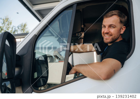 Sitting in a van and smiling. Courier of delivery service company is at work 139231402