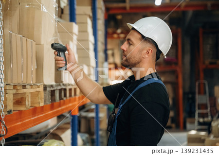 Scanning the boxes. Man in uniform is working in the storage with packages for shipment Scanning the boxes. Man in uniform is working in the storage with packages for shipment 139231435