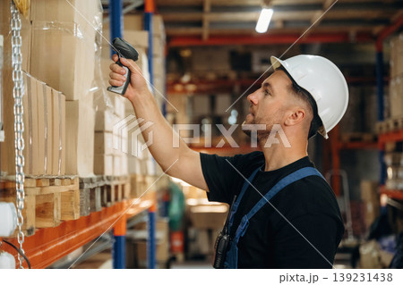Scanning the boxes. Man in uniform is working in the storage with packages for shipment 139231438