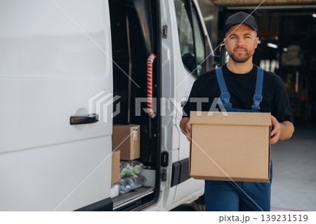 Delivery man is by the bus near garage outdoors Delivery man is by the bus near garage outdoors 139231519