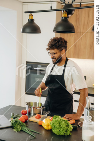 Mixes ingredients in a bowl. Handsome man is preparing food on the kitchen 139231818