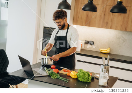 Mixes ingredients in a bowl. Handsome man is preparing food on the kitchen Mixes ingredients in a bowl. Handsome man is preparing food on the kitchen 139231823