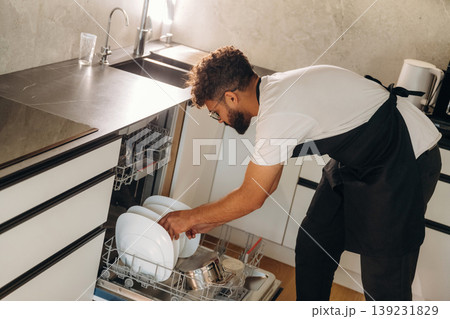Side view. Man putting dirty dishes in the dishwasher 139231829