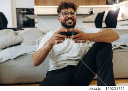 Enjoying playing video games, with controller. Man is in the modern domestic room at home 139231881
