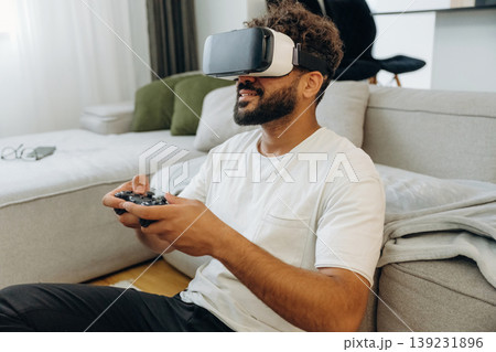 Virtual reality glasses, controller in hands. Man is in the modern domestic room at home 139231896