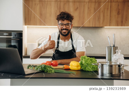 Standing and smiling. Handsome man is preparing food on the kitchen 139231989