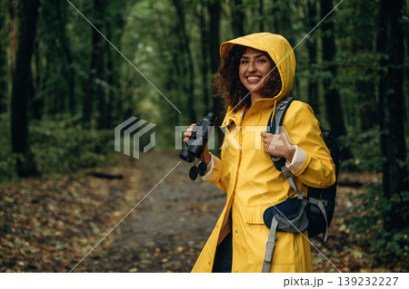 The binoculars, conception of discovery. Young woman enjoying nature in the forest under the rain The binoculars, conception of discovery. Young woman enjoying nature in the forest under the rain 139232227