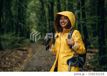 The binoculars, conception of discovery. Young woman enjoying nature in the forest under the rain The binoculars, conception of discovery. Young woman enjoying nature in the forest under the rain 139232228