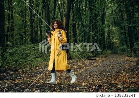 Professional photographer is with camera. Young woman enjoying nature in the forest under the rain 139232241