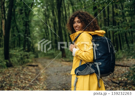 Hiking conception, with backpack. Young woman enjoying nature in the forest under the rain Hiking conception, with backpack. Young woman enjoying nature in the forest under the rain 139232263