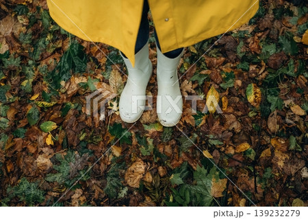 Close up view of woman legs, in rainy forest, yellow raincoat and rubber boots 139232279