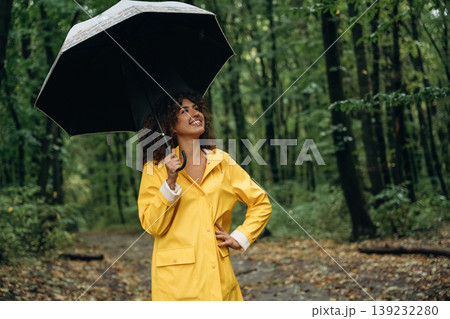 Non urban scene, holding umbrella. Young woman enjoying nature in the forest under the rain Non urban scene, holding umbrella. Young woman enjoying nature in the forest under the rain 139232280
