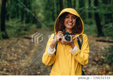 Photographer is with camera. Young woman enjoying nature in the forest under the rain 139232310