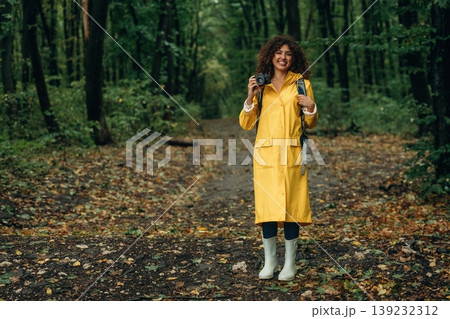 Photographer is with camera. Young woman enjoying nature in the forest under the rain Photographer is with camera. Young woman enjoying nature in the forest under the rain 139232312
