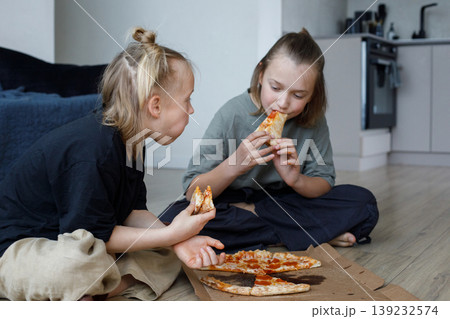 Hungry kids sibling eating pizza at home. Little girl and boy children portrait 139232574