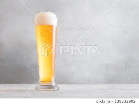 Glass pint of cold fresh lager beer with foam on light table background. Glass pint of cold fresh lager beer with foam on light table background. 139232902