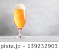 Glass of lager cold fresh preium beer with foam on light table background. 139232903