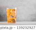 Glass of cold natural apple cider with ice cubes on light table background. 139232927