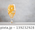 Glass of cold natural apple cider with ice cubes on light table background. 139232928