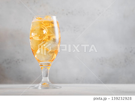 Glass of cold natural apple cider with ice cubes on light table background. 139232928