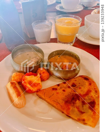 南インド・ケララ州のリゾートで楽しむ朝食。本格的なインドカレーとパラタ、ソーセージの洋印折衷プレート 南インド・ケララ州のリゾートで楽しむ朝食。本格的なインドカレーとパラタ、ソーセージの洋印折衷プレート 139233948