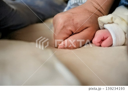 赤ちゃんの拳と大人の手の力強い絆・健やかな成長と育児の日常 139234193
