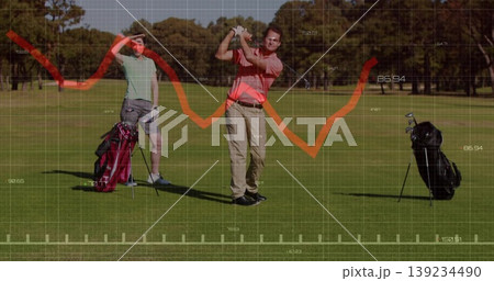 Swinging mature male golfer hitting golf ball past two golf bags on fairway, with analytics overlay Swinging mature male golfer hitting golf ball past two golf bags on fairway, with analytics overlay 139234490