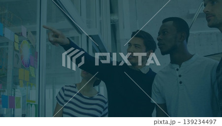 Pointing man in navy sweater highlighting color wheel on glass whiteboard in office, sticky notes 139234497