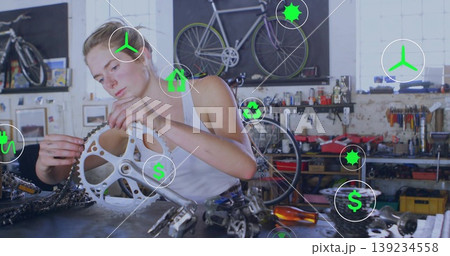 Bicycle mechanic fitting bicycle chainring onto crankset at repair shop workbench, with wrenches 139234558