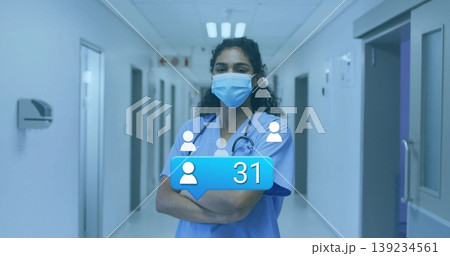 Standing female nurse in scrubs and mask in hospital corridor, with stethoscope and UI notification Standing female nurse in scrubs and mask in hospital corridor, with stethoscope and UI notification 139234561