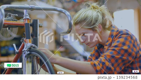Truing female mechanic adjusting bicycle wheel in repair workshop, with road bike and toolbox 139234568