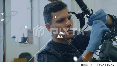 Leaning bicycle mechanic adjusting frame handlebars in shop, with blue gloves and digital overlays Leaning bicycle mechanic adjusting frame handlebars in shop, with blue gloves and digital overlays 139234573