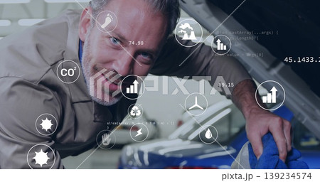 Cleaning adult male mechanic wiping engine bay inside garage, with blue cloth, digital eco icons Cleaning adult male mechanic wiping engine bay inside garage, with blue cloth, digital eco icons 139234574