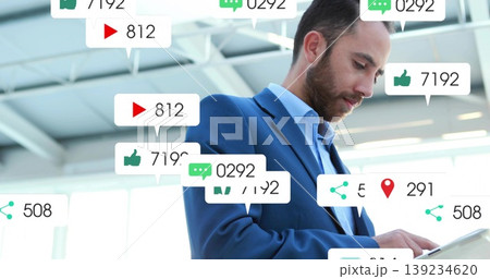 Business professional man holding tablet computer and viewing floating media icons in office lobby Business professional man holding tablet computer and viewing floating media icons in office lobby 139234620
