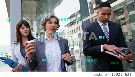 Walking team in suits discussing plan outside glass building with coffee cup blue binder laptop Walking team in suits discussing plan outside glass building with coffee cup blue binder laptop 139234621