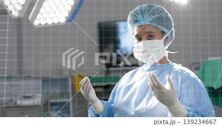 Surgeon in gown raising hands in OR, with light, monitor, tray, table and carts, copy space 139234667