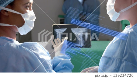 Examining two surgeons in surgical gowns reviewing spine X-ray film in operating room with overlay Examining two surgeons in surgical gowns reviewing spine X-ray film in operating room with overlay 139234720