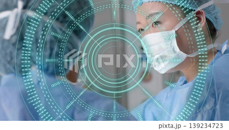 Korean female surgeon scanning AR interface in hospital OR, in blue scrubs, caps and masks Korean female surgeon scanning AR interface in hospital OR, in blue scrubs, caps and masks 139234723