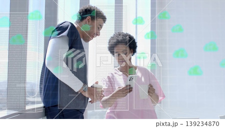 Standing pair wearing scrubs checking wristwatch and smartphone in lounge, digital overlay 139234870
