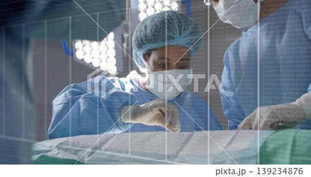 Mid adult surgeon in blue gown making incision in operating room, with scalpel and forceps 139234876