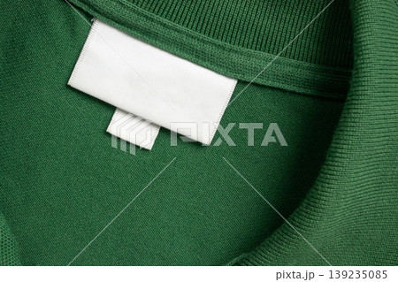 Blank white laundry care clothes label on green shirt fabric texture background Blank white laundry care clothes label on green shirt fabric texture background 139235085