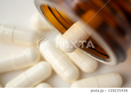 medicine pills capsule spilling out of bottle on white background medicine pills capsule spilling out of bottle on white background 139235436