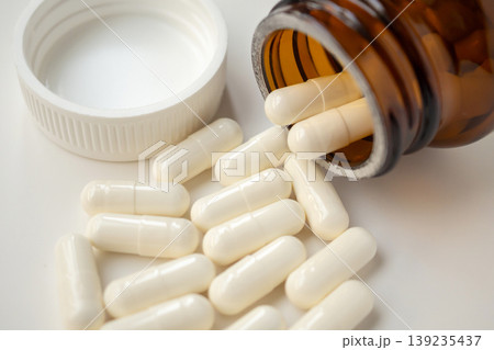 medicine pills capsule spilling out of bottle on white background 139235437