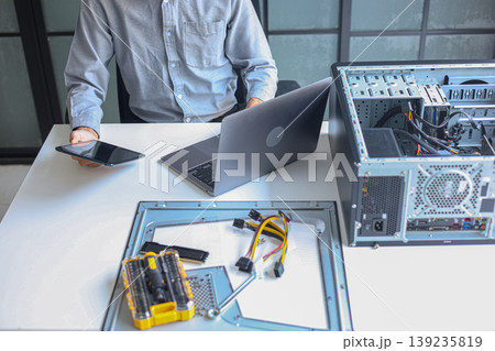 IT technician using tablet and laptop while repairing computer motherboard and computer hardware components. IT technician using tablet and laptop while repairing computer motherboard and computer hardware components. 139235819