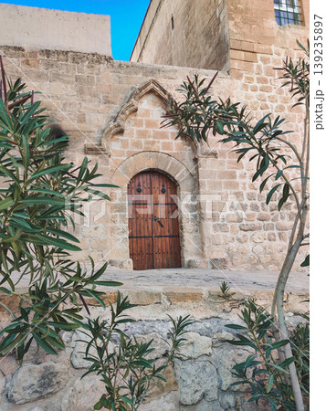 Ancient arched wooden door in the historic stone walls of Mardin Ancient arched wooden door in the historic stone walls of Mardin 139235897