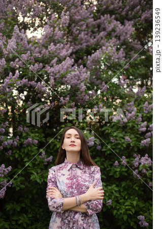 Young woman looking up in front of blooming lilac bushes Young woman looking up in front of blooming lilac bushes 139236549